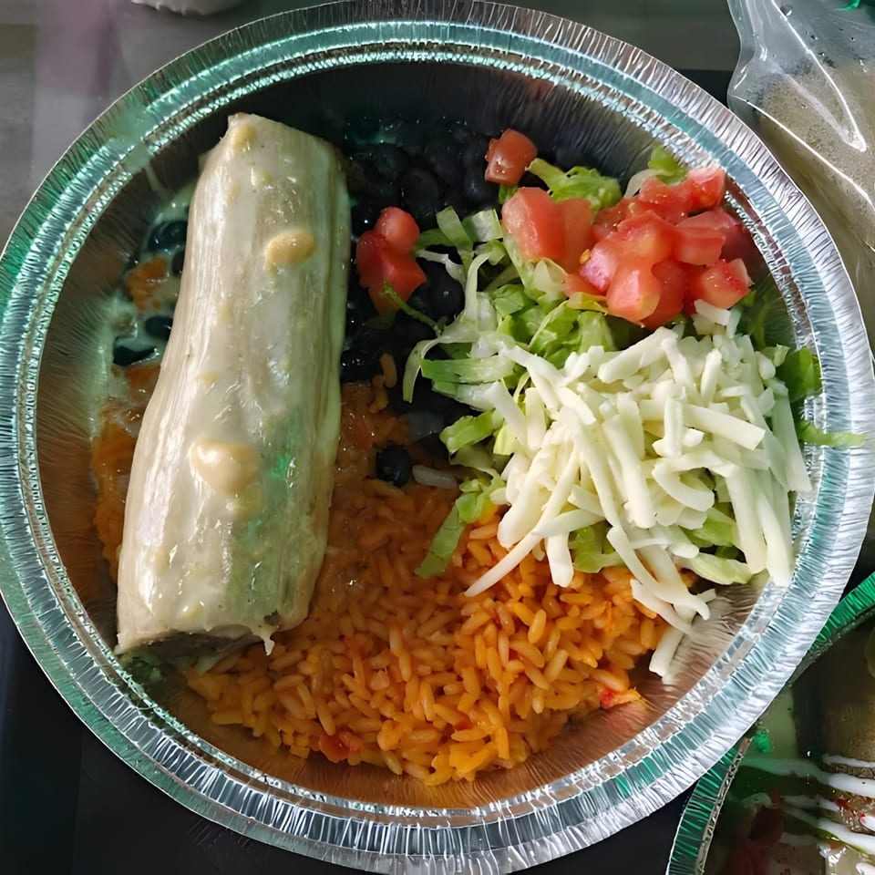 Tamales Inc. tamale meal with rice, black beans, lettuce, tomatoes, and shredded cheese in a foil container.