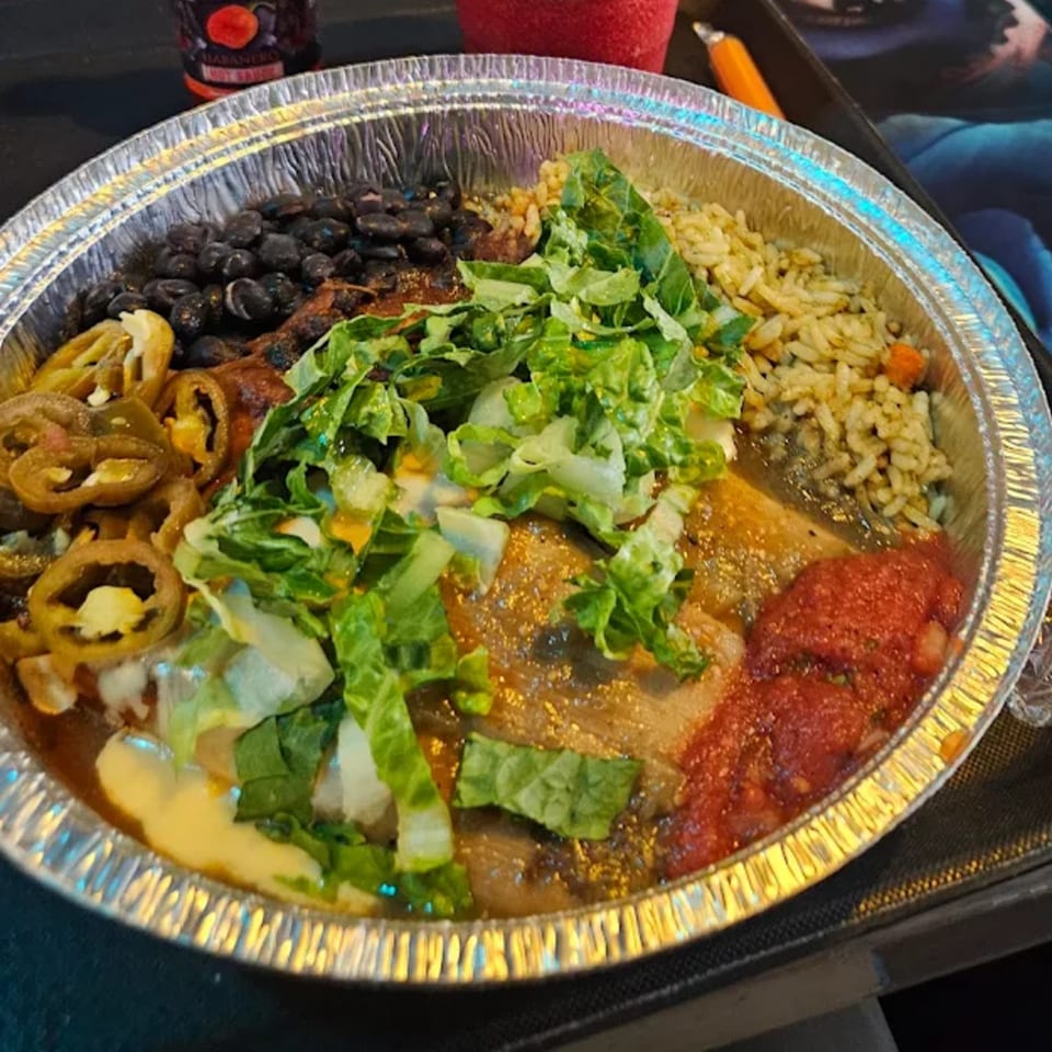A Tamales Inc. meal in a foil container with tamales, black beans, rice, salsa, lettuce, and jalapeños.