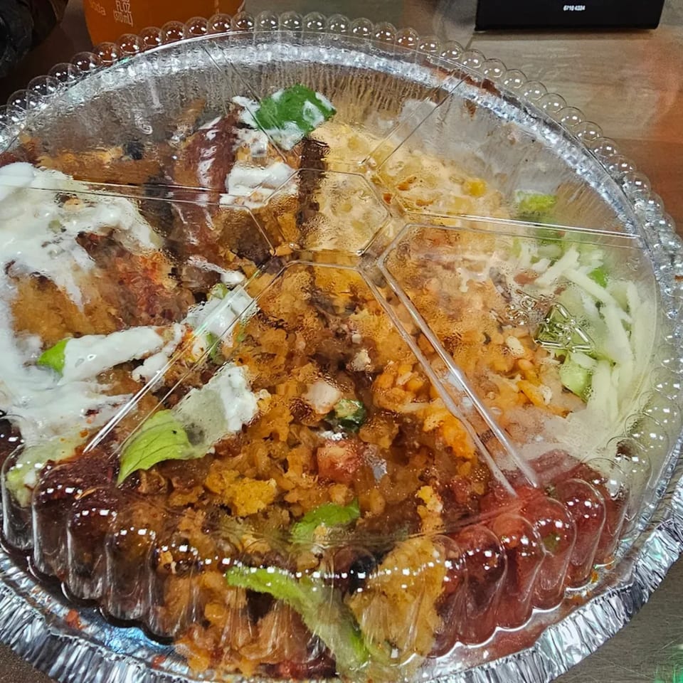 Tamales Inc's Mexican food in a foil container with a clear, sectioned plastic lid.